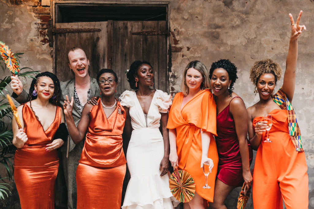 stunning bride in wedding gown with bridal party in orange dresses