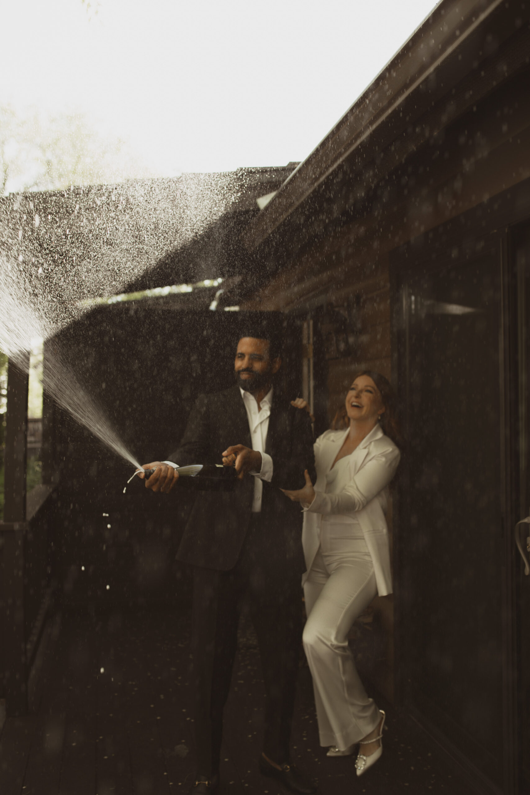 Happy couple spraying a champagne bottle
