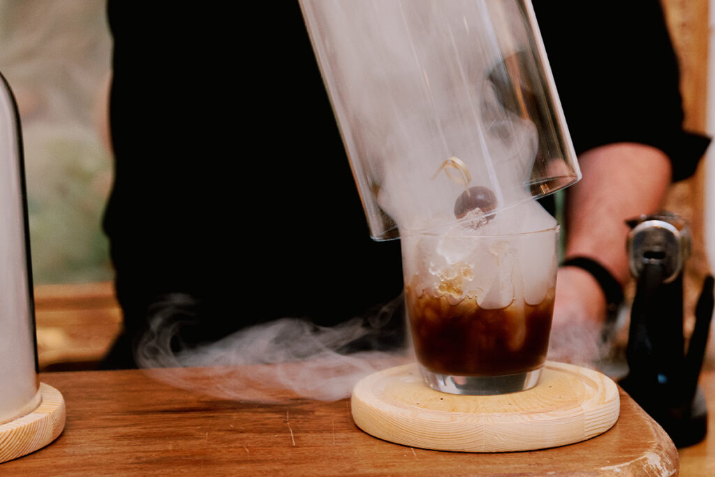 A smoked cocktail served by a mixologist. To get some pats on the back from your guests, offer a self-service bar where people are free to pick and pour their drinks as they please. You can also seek a mixologist who can create custom cocktails for a personalized touch.