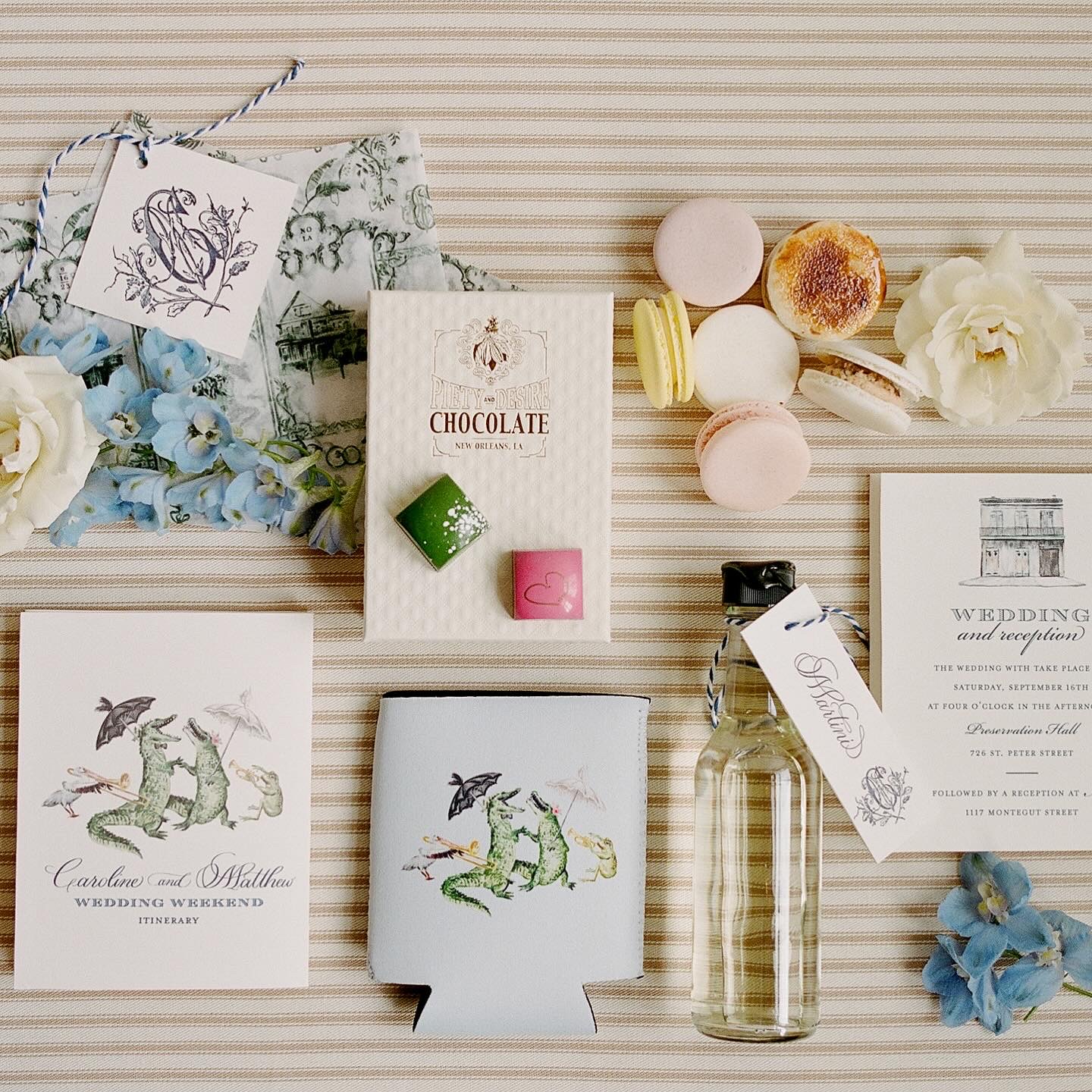 Assorted welcome bag items laid out, including chocolates, macarons, custom-printed materials, and floral decorations.