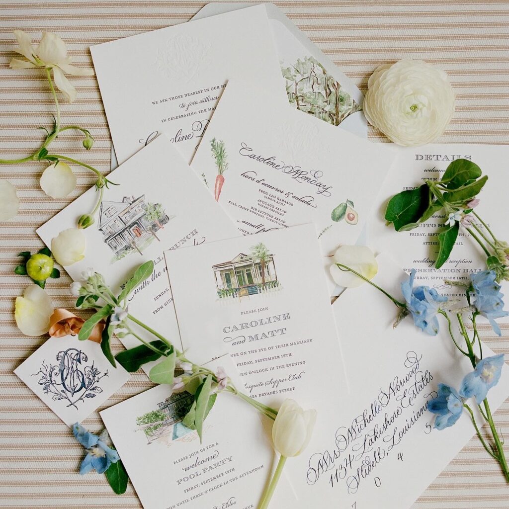 An elegant spread of wedding stationery including invitations and detail cards among fresh flowers.