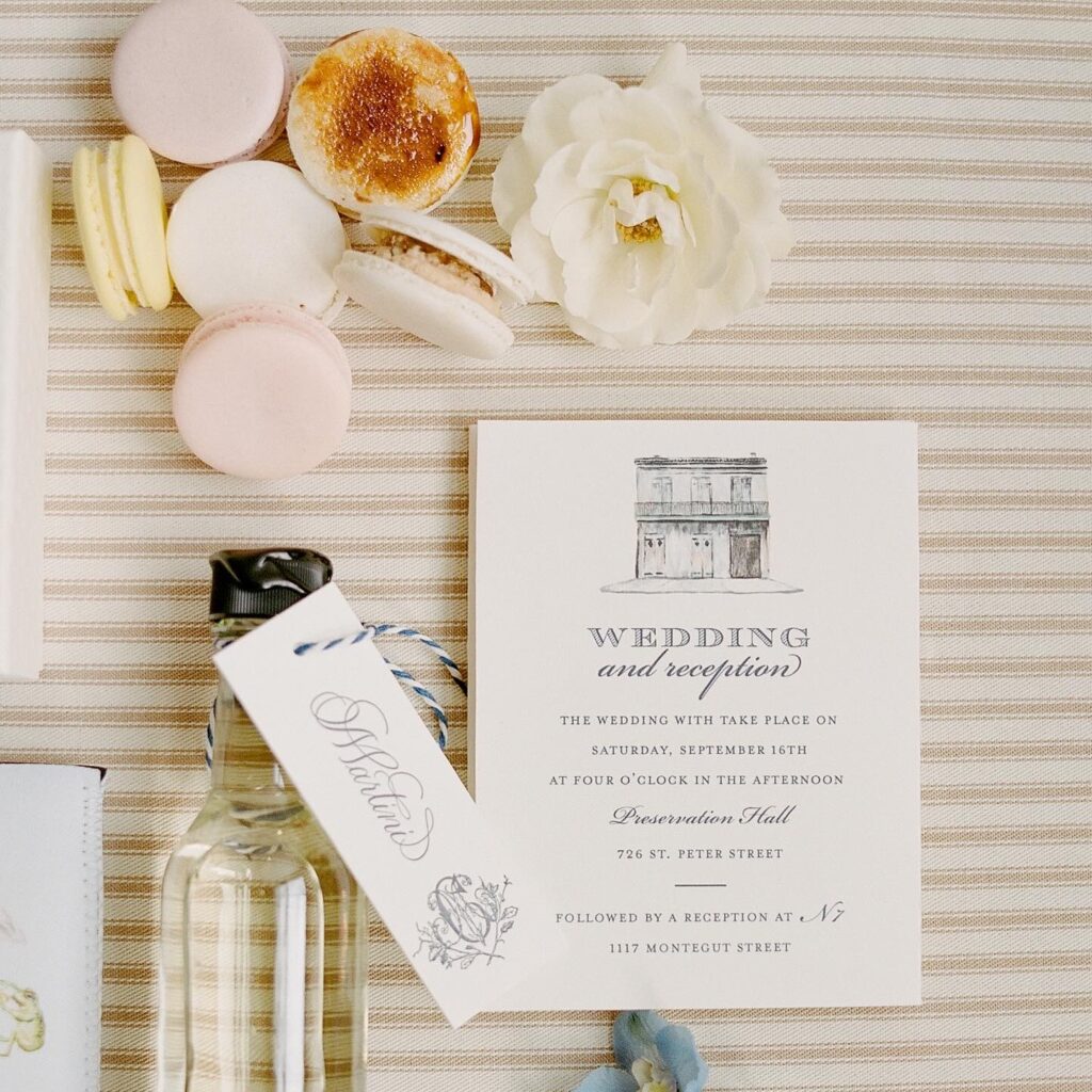 Close-up view of wedding welcome bag contents with macarons, a white rose, and a wedding reception card.